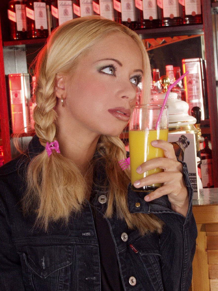 Blondine mit Zöpfen hält Cocktailglas in der Hand